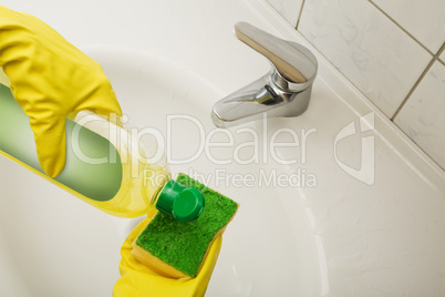 Hausfrau reinigt das Waschbecken mit Putzmittel
