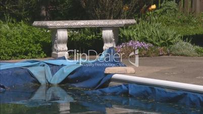 Corner of winterized pool with tarp and stone bench