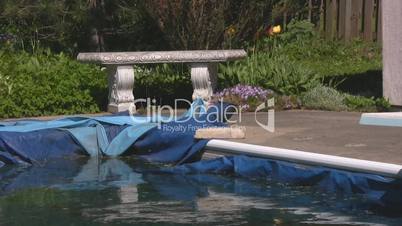 Stone bench and winterized pool in backyard zoom out