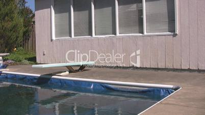 Corner of closed pool with diving board and shed