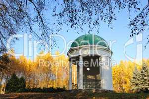 Pavilion in a park with yellow birch tree and blue sky on backgr