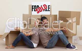Wife and husband relaxing on floor unpacking boxes