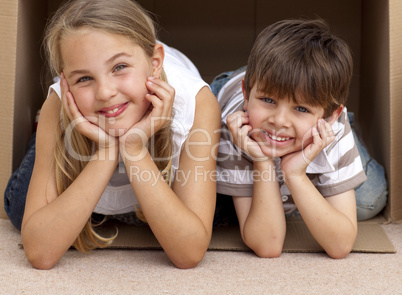 Siblings playing with boxes after moving house