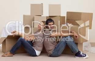 Smiling couple sitting on floor around boxes