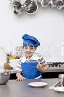 Little boy with blue hat and apron baking