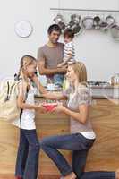 Mother giving girl the school lunch in the kitchen