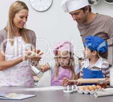 Mother and father helping children baking in the kitchen