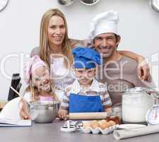 Smiling parents helping children baking in the kitchen