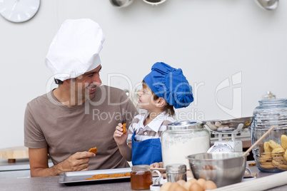 Smiling father and son eating home-made cookies