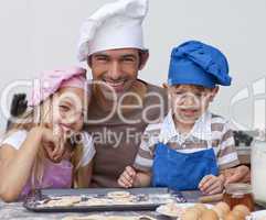 Happy father and children baking cookies together