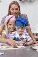 Mother helping her children baking