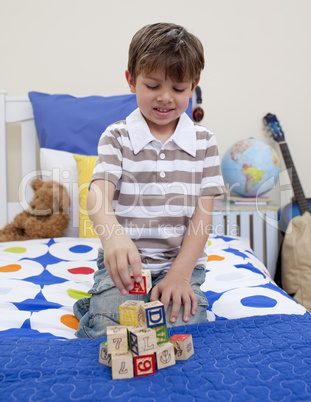 Little boy playing with alphabet cubes in his bedroom