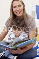 Smiling mother reading a book with her son