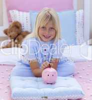 Smiling girl saving money in a piggy bank