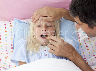 Father checking his daughter's temperature with a thermometer