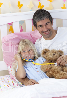 Daughter and father playing with a stethoscope and a teddy bear