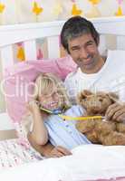 Daughter and father playing with a stethoscope and a teddy bear