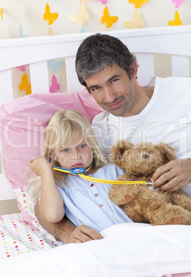 Sick girl playing with a stethoscope with her father