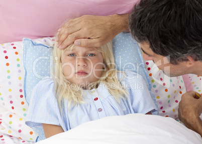 Father taking his daughter's temperature in bed