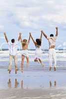 Four Young People, Two Couples, Jumping in Celebration On Beach