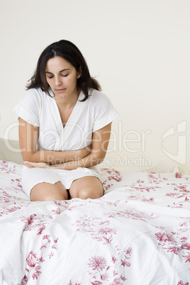 Junge hübsche Frau mit Bauchschmerzen im Bett
