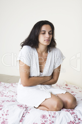 Frau mit Bauchschmerzen im Bett