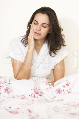 Junge hübsche Frau mit Zahnschmerzen im Bett