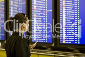 Hübsche Frau am Flughafen vor einem Informationsbildschirm