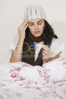 Junge Frau krank im Bett beim Themperatur messen