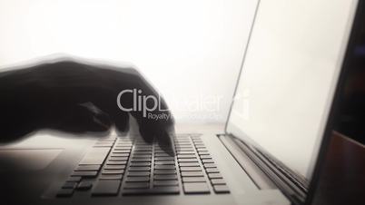 Silhouette typing on computer keyboard timelapse