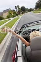 Young Woman Driving Convertible Car With Hand In The Air