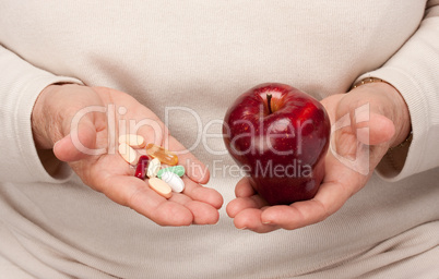 Senior Woman Holding Pills and Apple