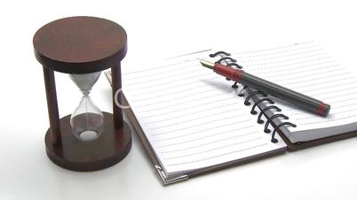 Hourglass, pen and lined notebook