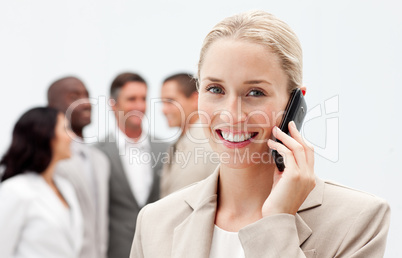 Blonde businesswoman on mobile with her team in the background