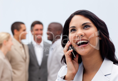 Happy businesswoman on phone with her team in the background