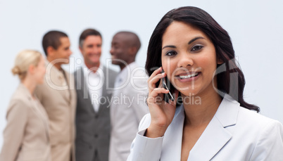 Ethnic businesswoman on phone with her team in the background
