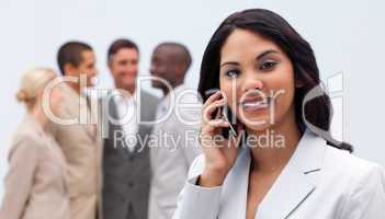 Ethnic businesswoman on phone with her team in the background