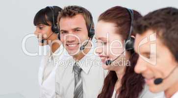 Smiling man working in a call center with his colleagues