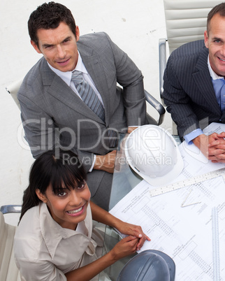 High angle of multi-ethnic architects working with blueprints