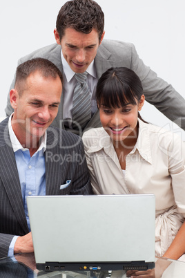 Two businessmen and a businesswoman using a laptop