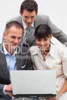 Two businessmen and a businesswoman using a laptop