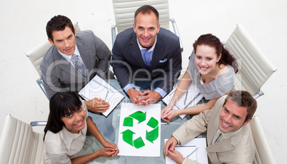 High angle of smiling business team holding a recycling symbol