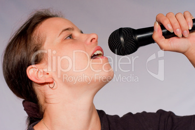 Junge Frau singt in Mikrofon