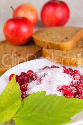 Cowberry sprinkled with sugar against apples and bread