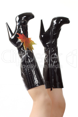Female feet in black boots on a high heel with autumn sheet