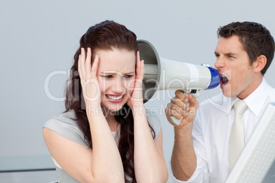 Businessman yelling through a megaphone at a businesswoman