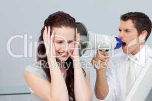 Businessman yelling through a megaphone at a businesswoman