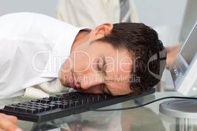 Businessman sleeping on the keyboard in the office