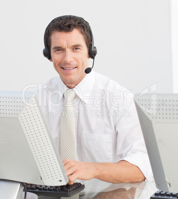 Smiling businessman with a headset on in a call center