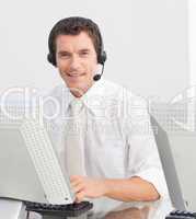 Smiling businessman with a headset on in a call center